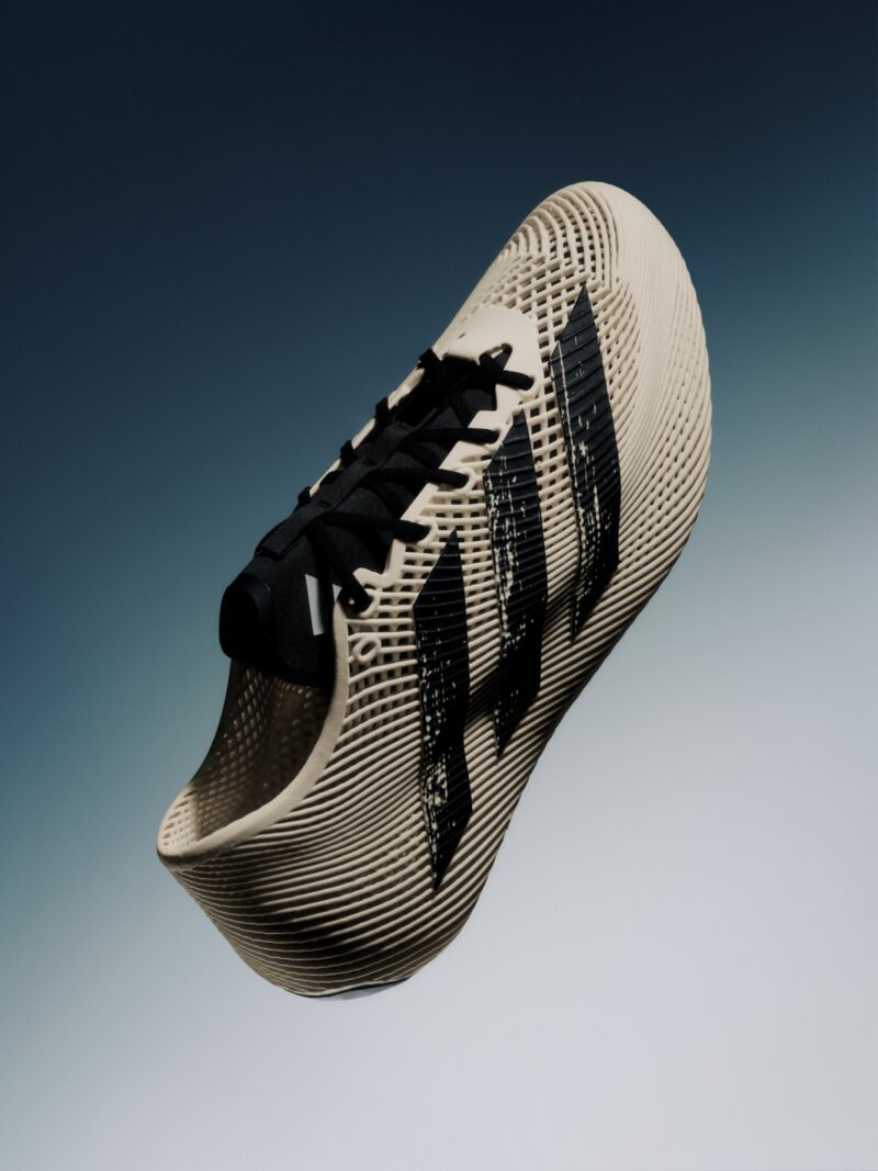 Beige adidas Climacool Laced sneaker with black laces and three black stripes, featuring a textured, futuristic design, displayed against a gradient blue background.