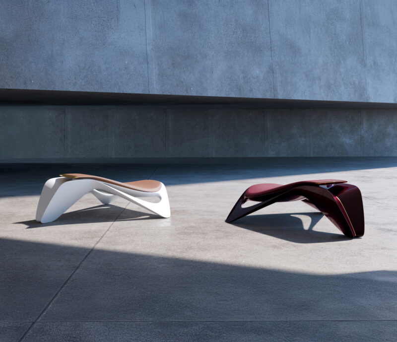Two modern, sculptural benches—one white and one dark red, from the Ennua Element 01 collection—sit on a concrete surface against a plain gray wall, partially in shadow.