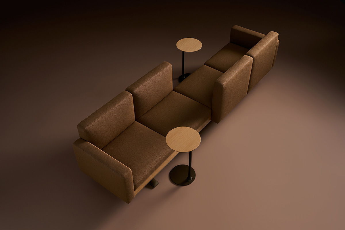 Two brown sofas are positioned back-to-back with two round wooden side tables, each table next to one sofa, on a brown floor.