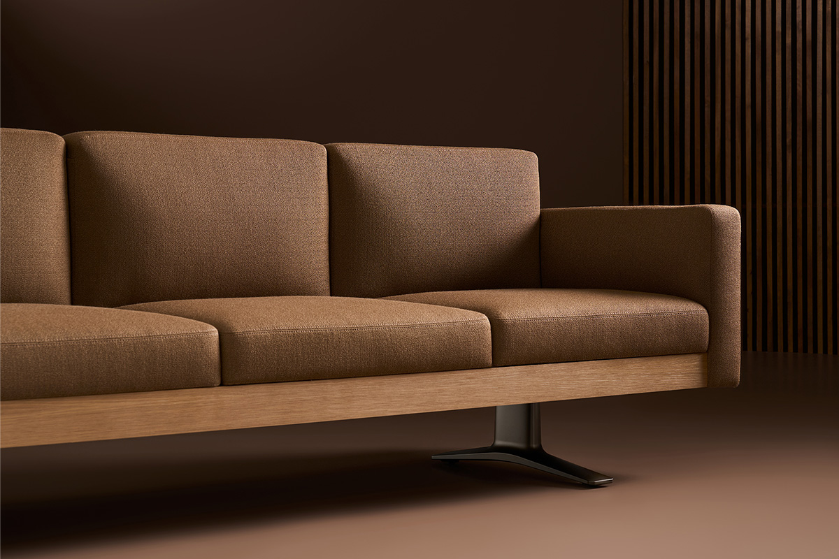 Brown three-seat sofa with wooden base and single black metal leg, set against a brown wall with vertical wooden slats on the right.