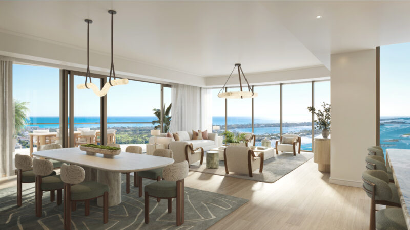 Modern open-concept dining and living area with large windows, neutral decor, wood floors, and ocean views under natural light.