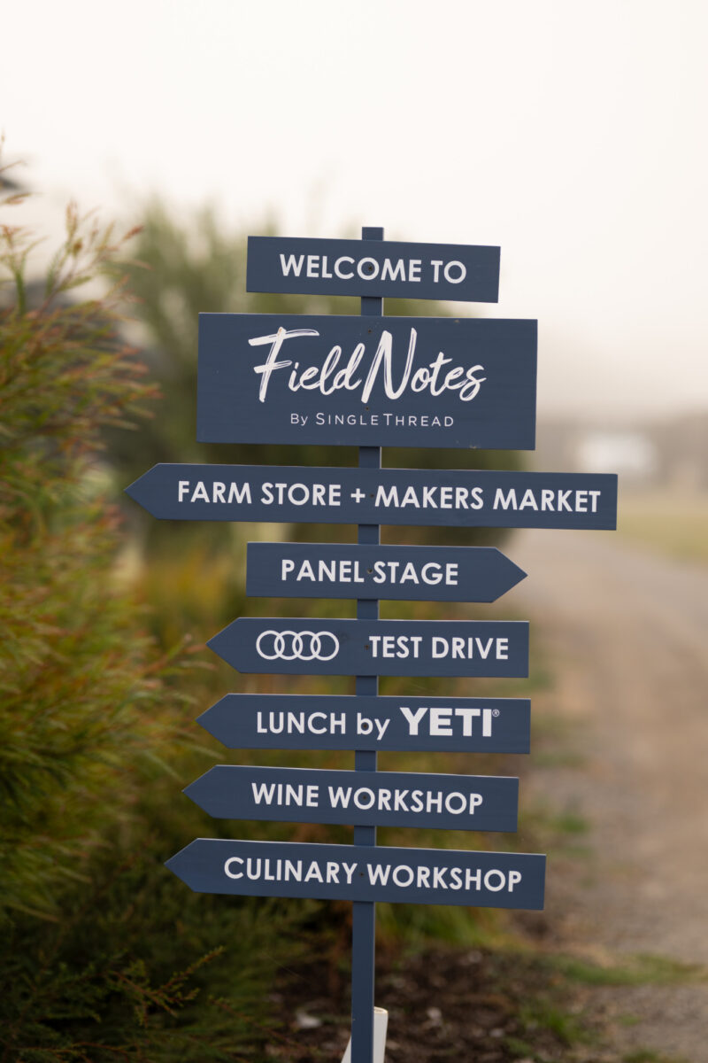 Directional signpost for Field Notes by SingleThread listing the Farm Store, Makers Market, Panel Stage, Audi Test Drive, Lunch by Yeti, Wine Workshop, and Culinary Workshop.