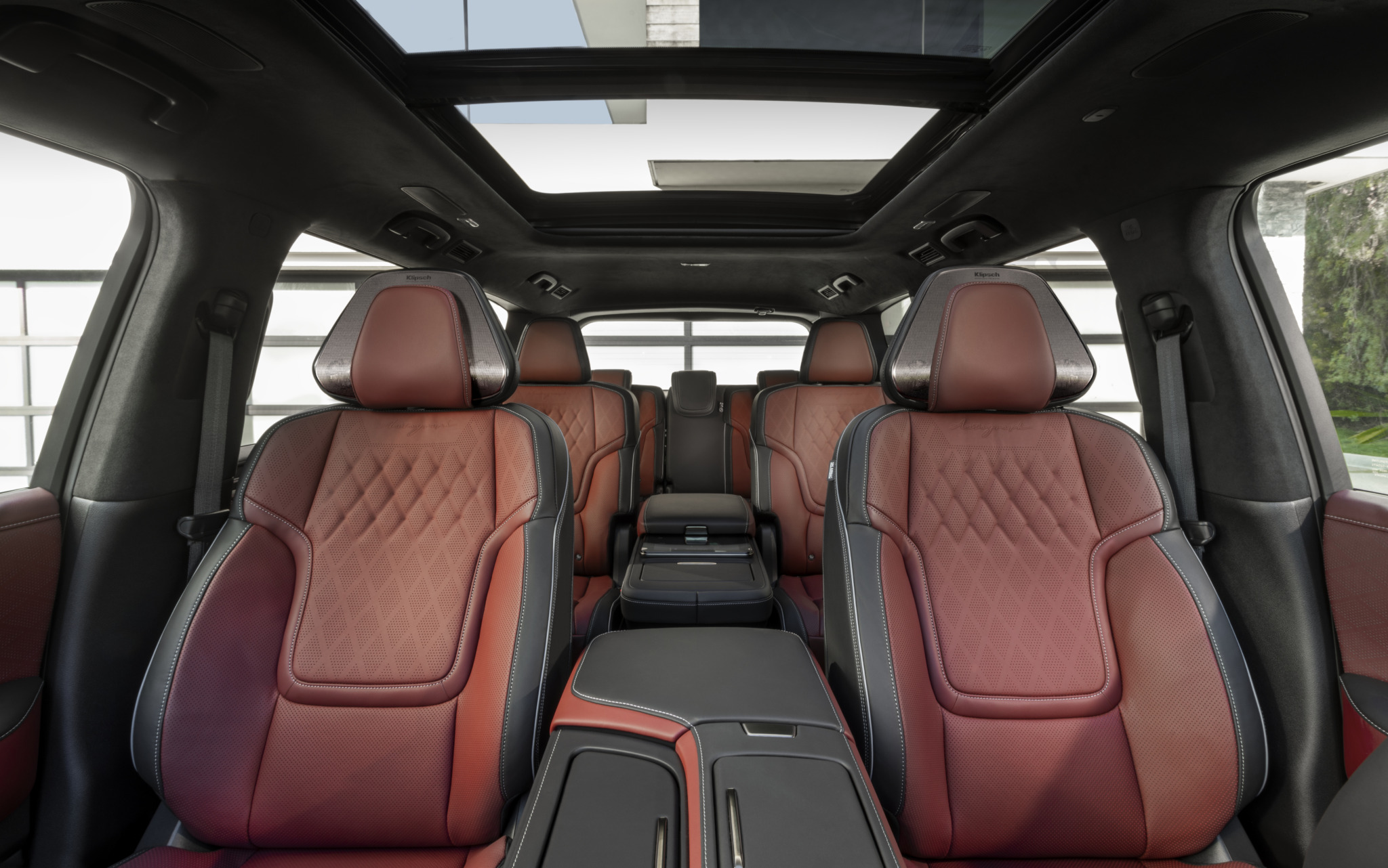 Interior view of a vehicle with maroon leather seats, a center console, and a panoramic sunroof.