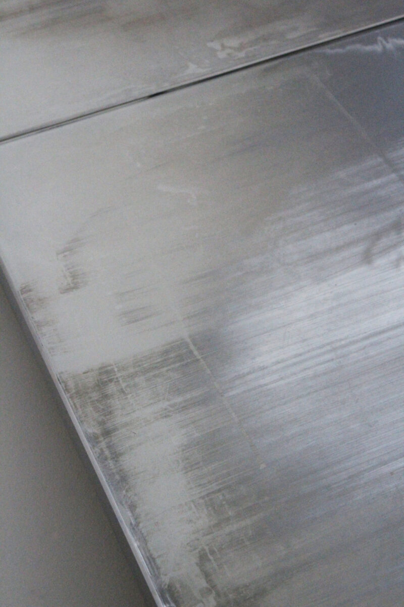 Close-up of a brushed metal surface with a visible horizontal seam.