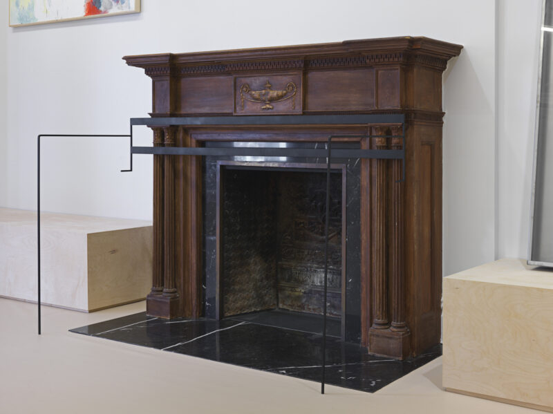 An ornate dark wood fireplace mantel with a black marble hearth and a metal safety railing.