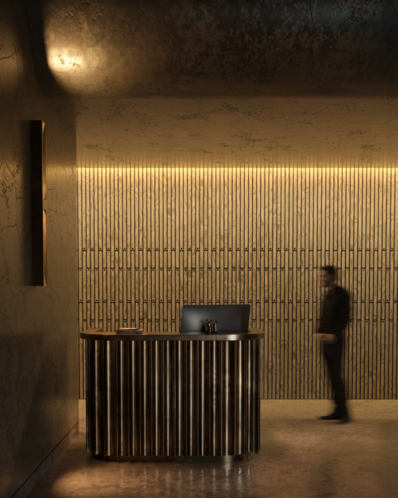 A receptionist desk with a ribbed metal base designed by Alfonso Verduzco sits in a dimly lit office lobby as a person walks past.