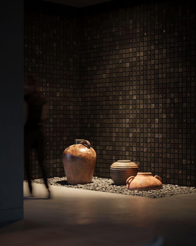 Three Alfonso Verduzco earthenware vessels sit on a bed of dark stones in front of a grid-patterned wall.