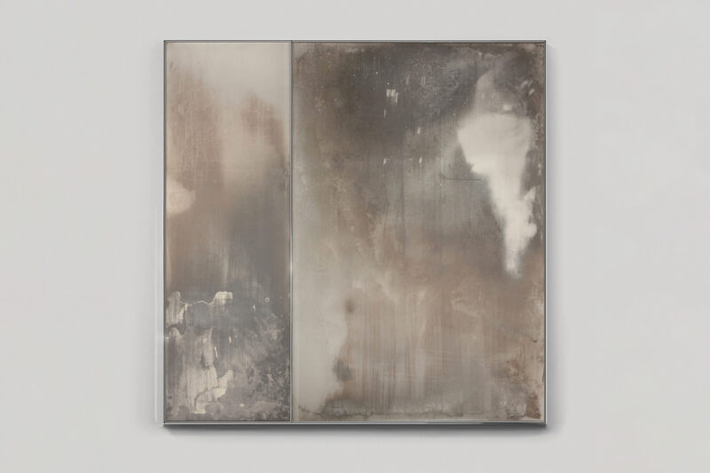Abstract painting in a metallic frame featuring vertical, brushed layers of muted gray and brown tones with a prominent white shape on the right.
